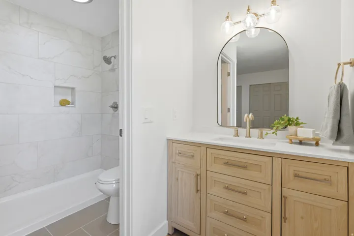 Wood-finish vanity with a white countertop and gold-toned faucet
