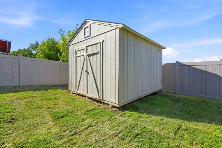 Outdoor storage shed featuring a gabled roof and a small window