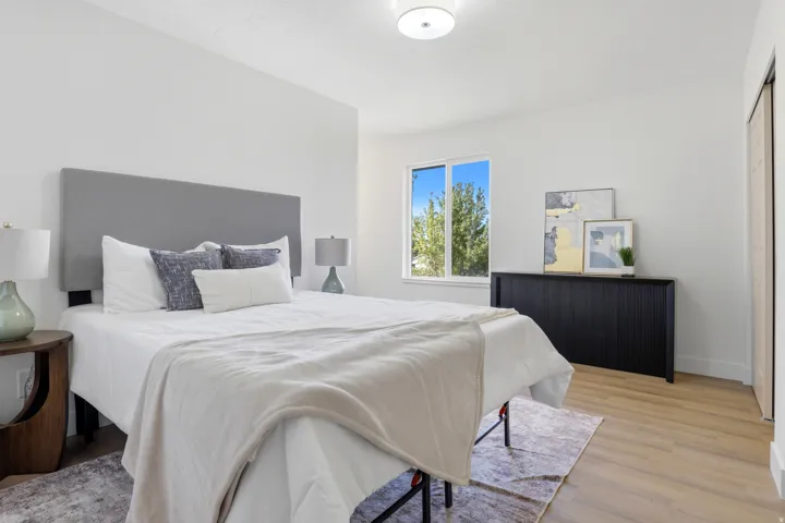 Light-toned wood-finish flooring, white walls, and a built-in dark wood-tone cabinet complement the window
