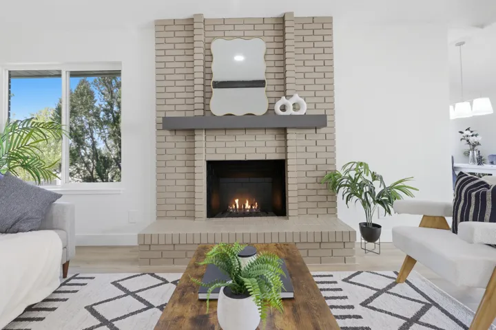 Brick fireplace with a dark mantel, wood-finish flooring, and white walls
