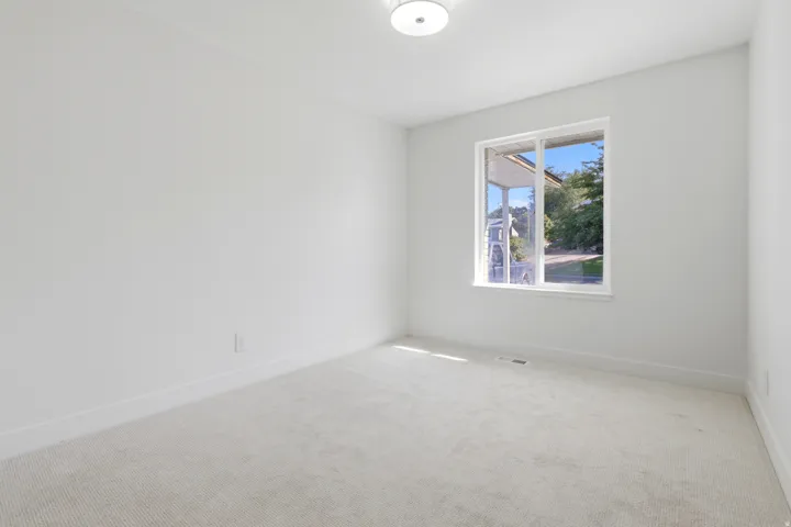 White walls, light-toned carpeting, and a white-framed window