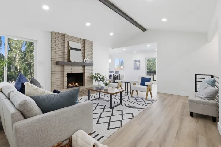Living area featuring a brick fireplace, vaulted ceiling with exposed beam, recessed lighting, and wood-finish flooring