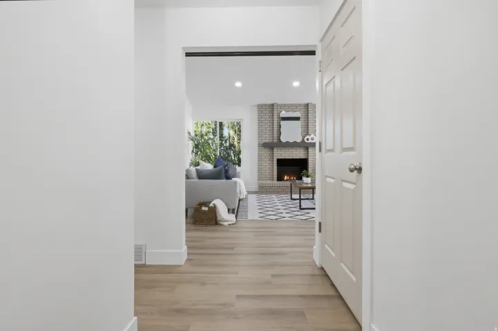 Wood-finish flooring throughout, bright white walls, and a recessed ceiling light