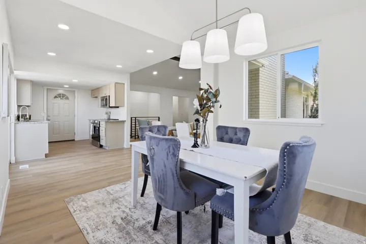 Spacious dining area with wood-finish flooring, recessed lighting, and a modern linear chandelier