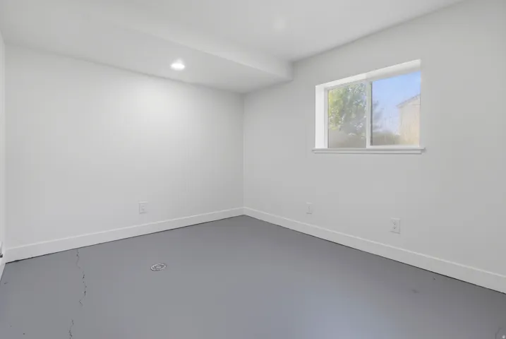 Recessed ceiling lighting, white painted walls, white trim, and a window providing natural illumination