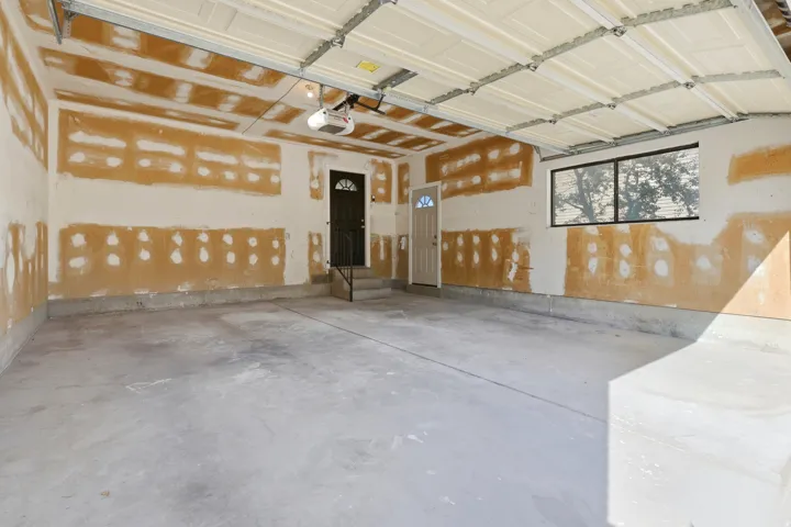 Concrete flooring, two entry doors, a window, and an automatic garage door opener