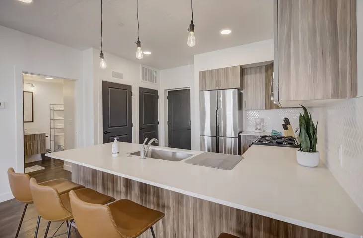 Kitchen featuring light wood-finish cabinetry, stainless steel appliances, white countertops, and a subway tile backsplash