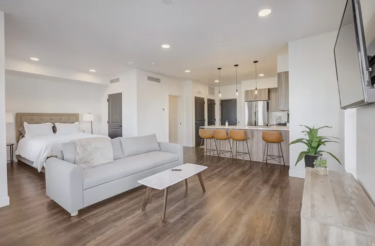 Open-concept living space with wood-finish flooring, recessed lighting, and a kitchen island featuring pendant lights
