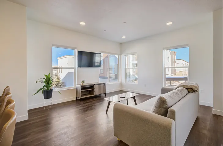 Spacious room featuring multiple large windows, recessed lighting, and dark wood-finish flooring