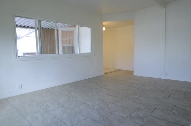 White walls, rectangular window, light-toned tile flooring, recessed archway, and an overhead light fixture