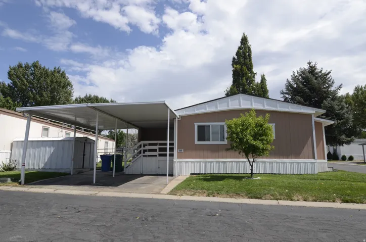 Single-story residence featuring a covered carport, exterior siding, white trim, and a manicured lawn