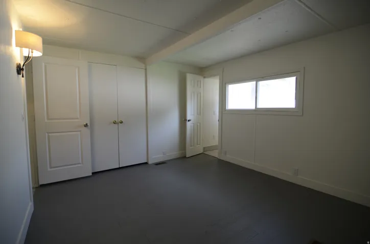 Dual closet doors, neutral wall paint, gray flooring, and a single window