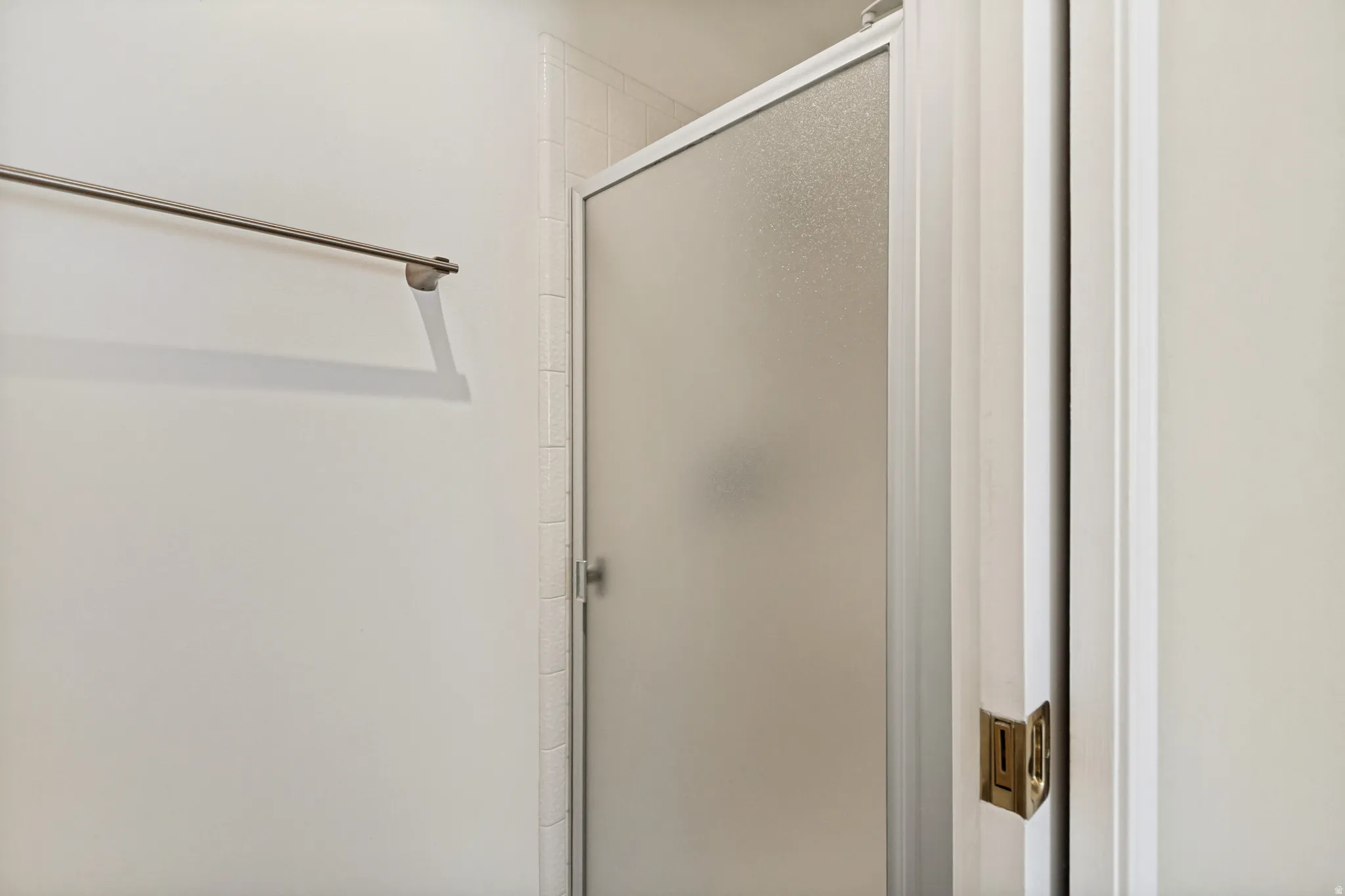 Frosted glass shower enclosure, white wall tiling, and a chrome towel bar