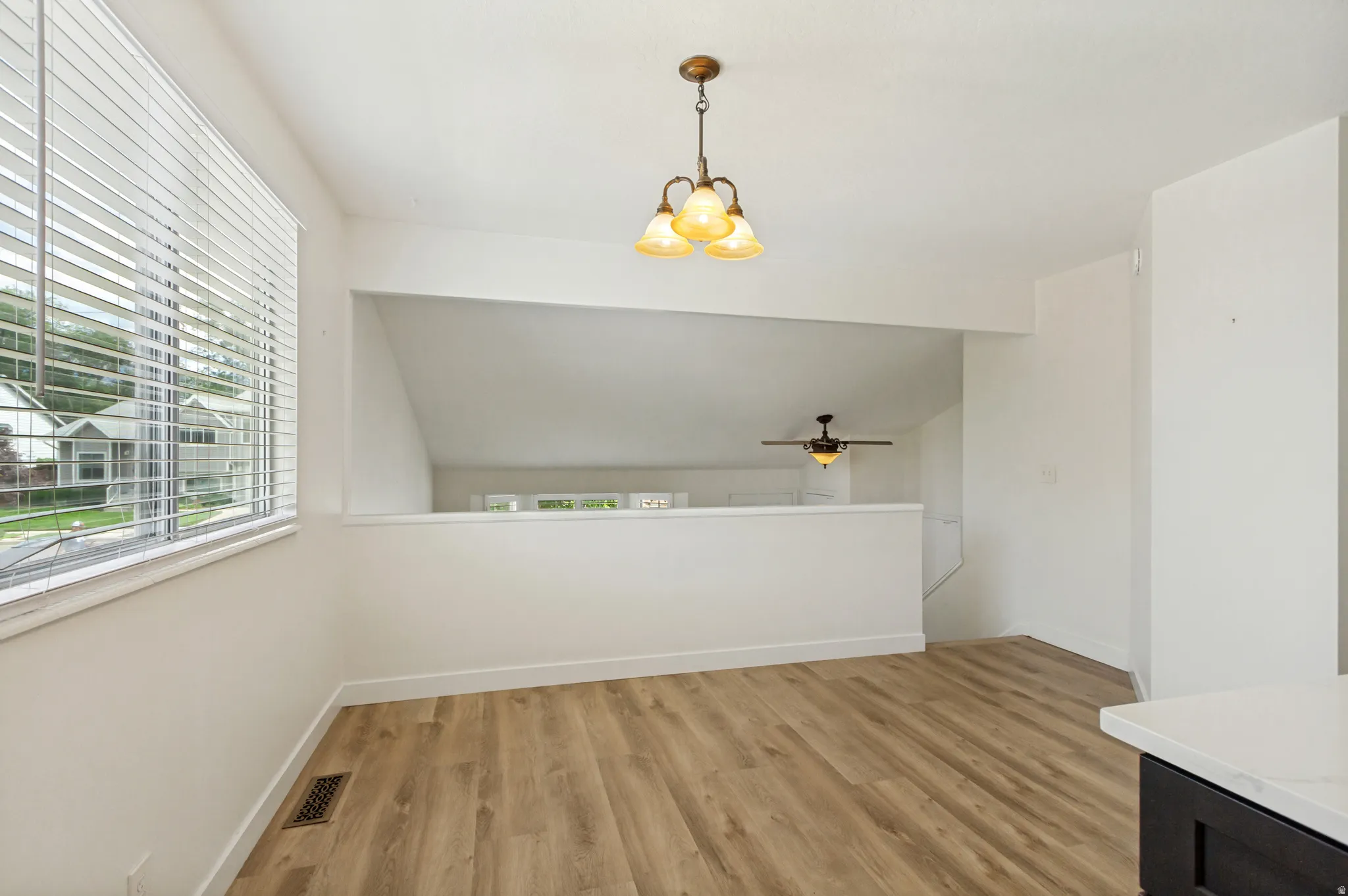 Wood-finish flooring, white walls, and a multi-light pendant fixture