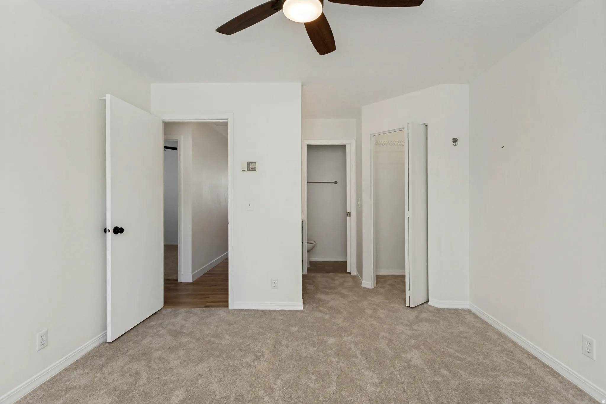Light-toned carpeted flooring throughout, ceiling fan with integrated lighting, and white walls