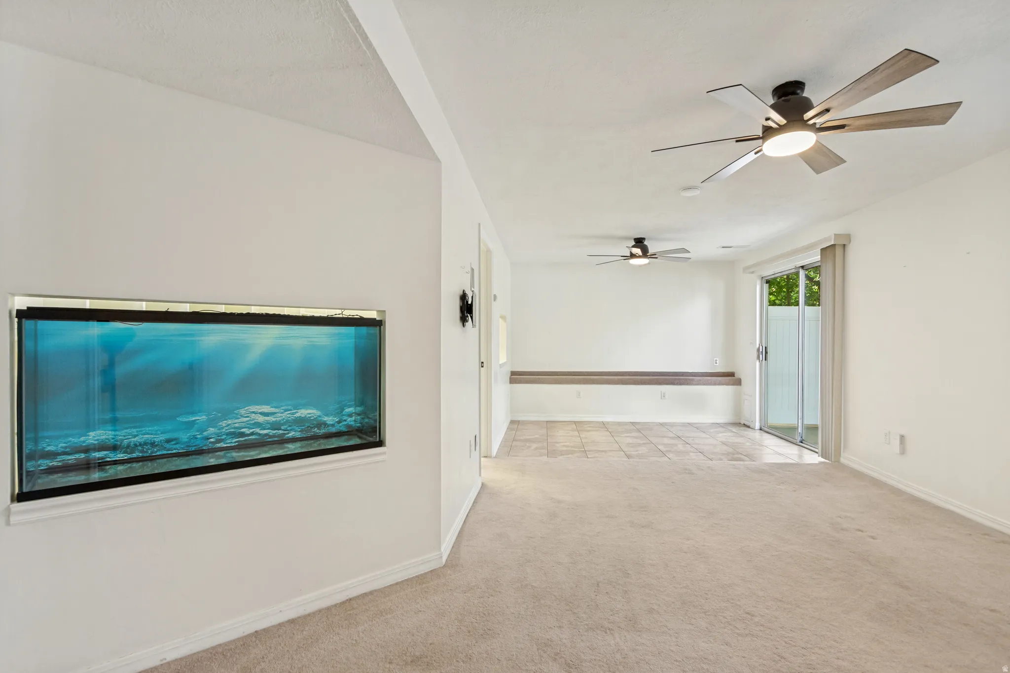 Built-in wall aquarium, two ceiling fans with integrated lighting, wood-finish built-in bench seating, ceramic tile flooring, and sliding glass door