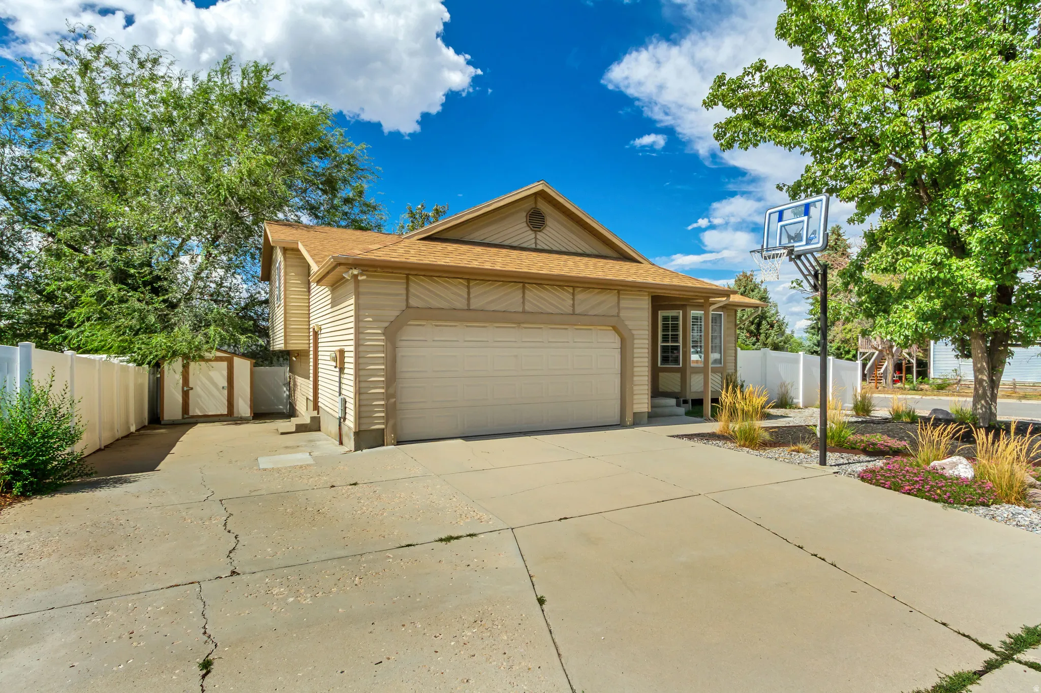Two-story property with attached garage, concrete driveway, and established landscaping