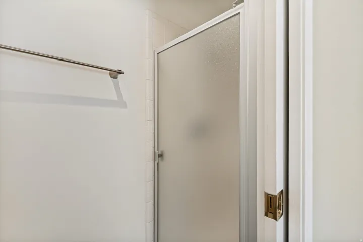 Frosted glass shower enclosure, white wall tiling, and a chrome towel bar