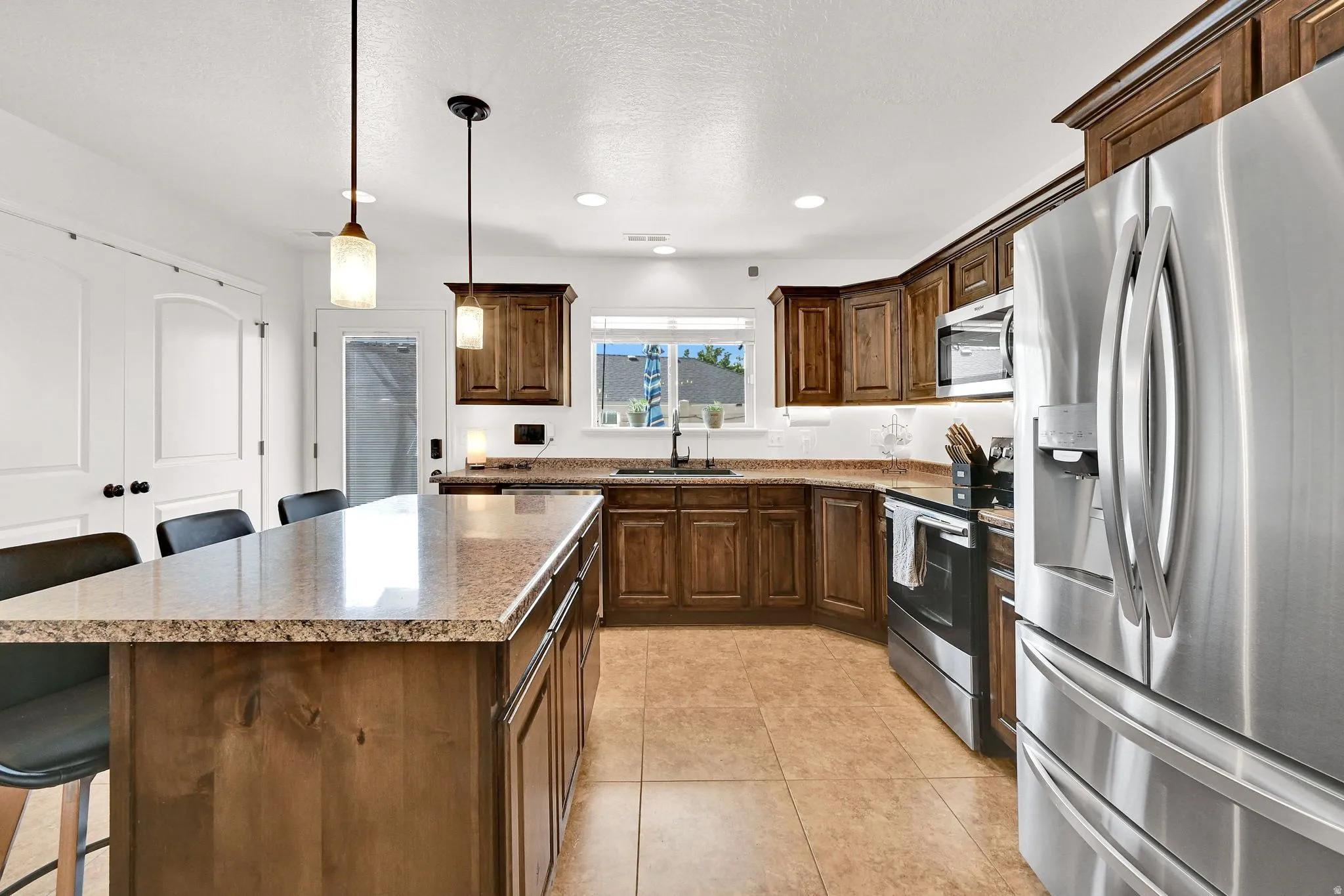 Kitchen featuring a central island with stone-finish countertop, wood cabinetry, stainless steel appliances, and recessed lighting