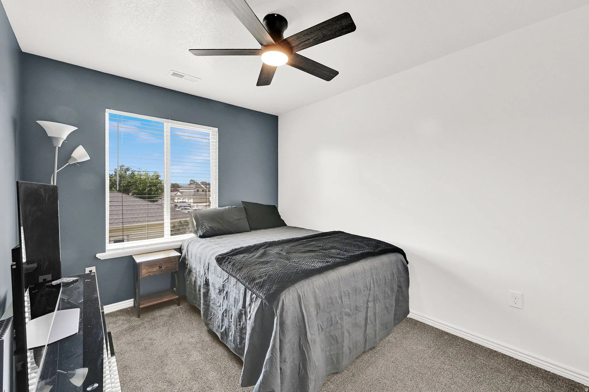 Window with blinds, wall-mounted ceiling fan with integrated lighting, and carpeted flooring
