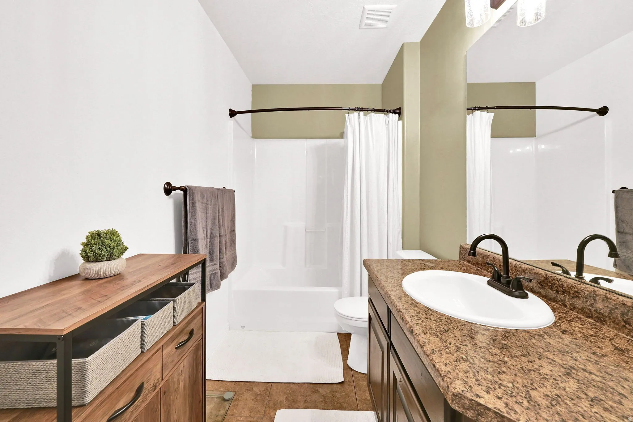 Vanity with an oval sink and a dark bronze faucet, accompanied by a granite-look countertop
