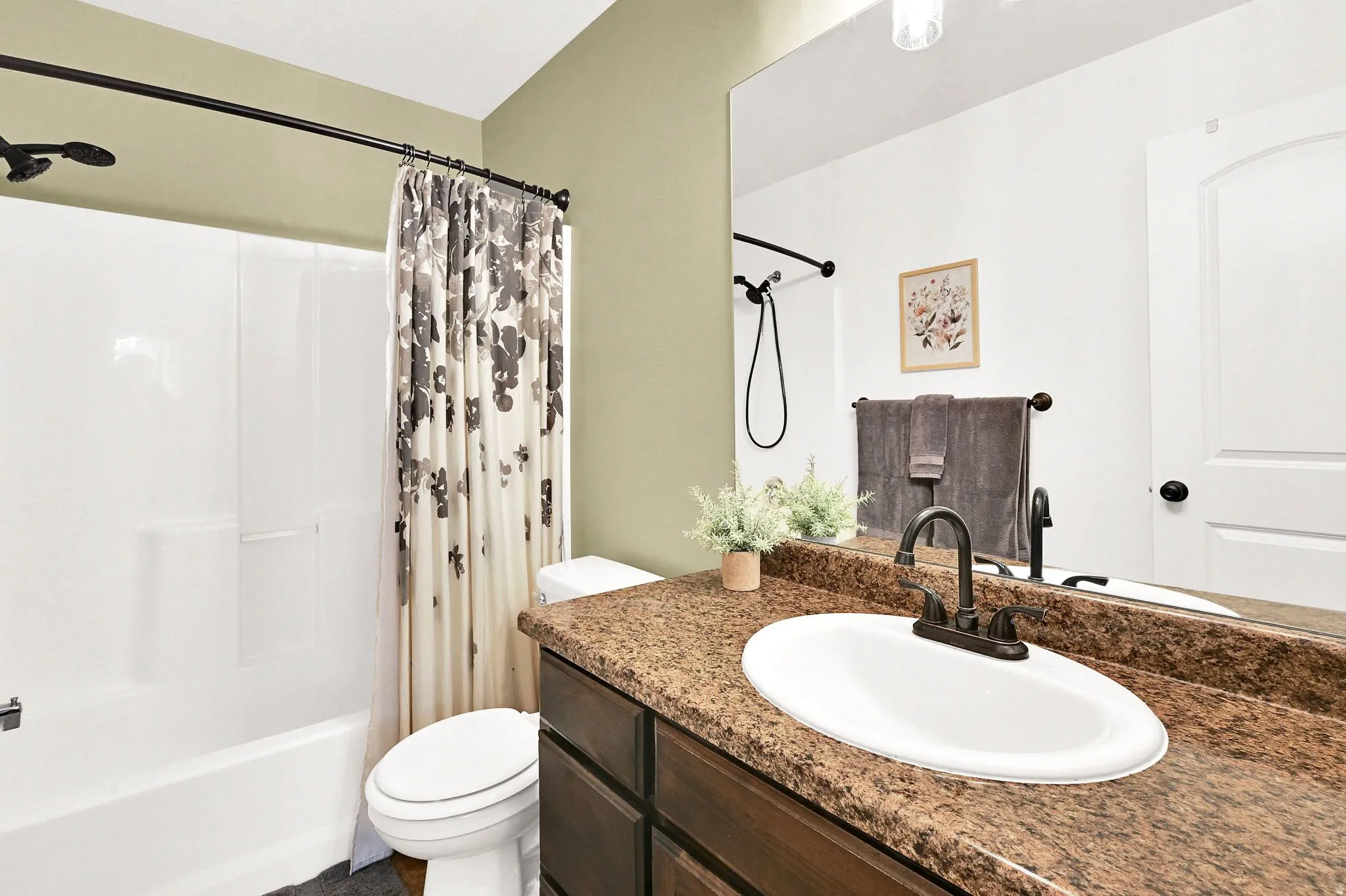 Bathroom featuring a white tub and shower combination, dark wood-finish vanity with an integrated sink, and a speckled countertop