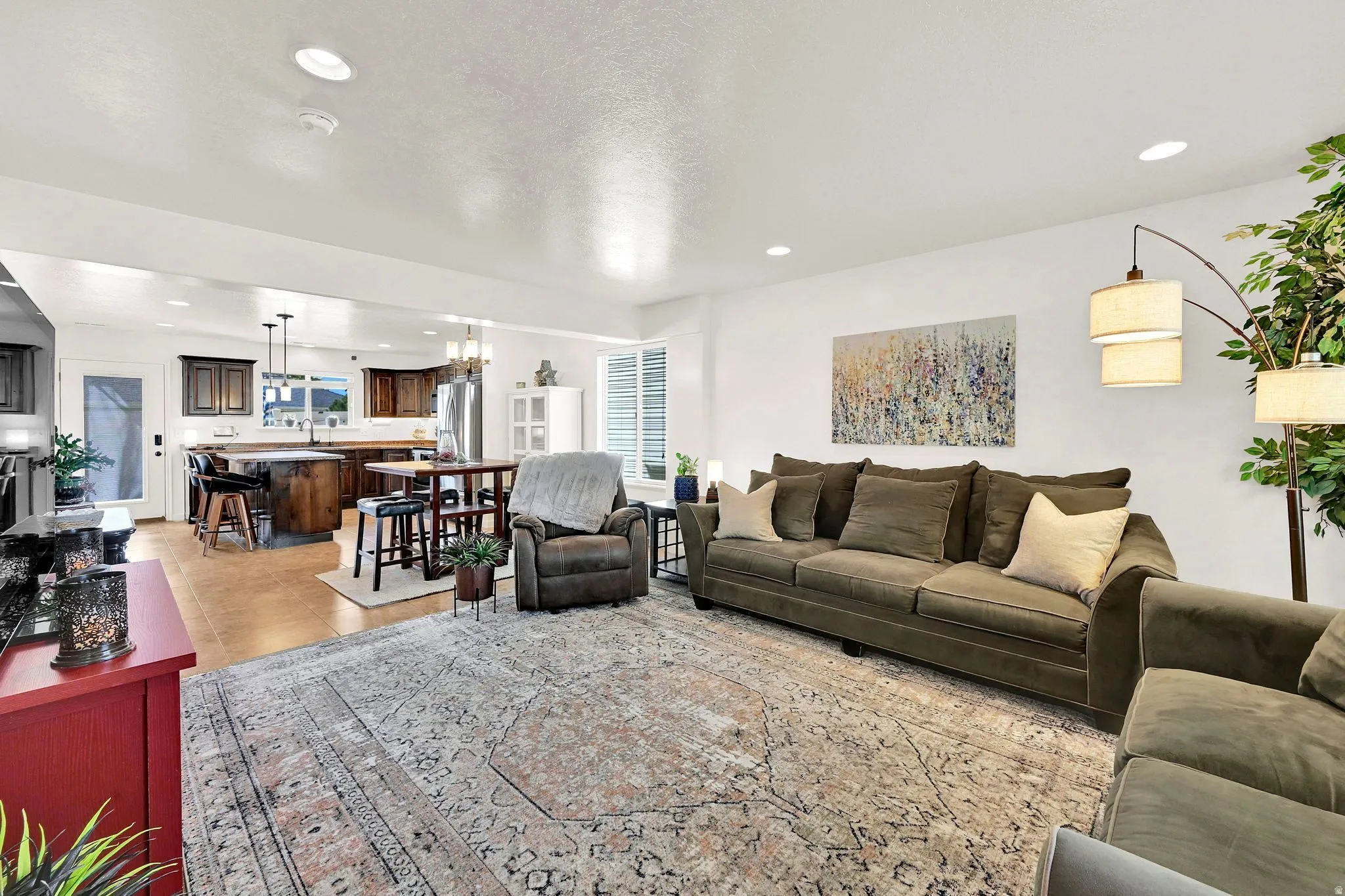 Recessed lighting, wood-finish flooring, dark wood cabinetry, window with plantation shutters, and a kitchen island with seating