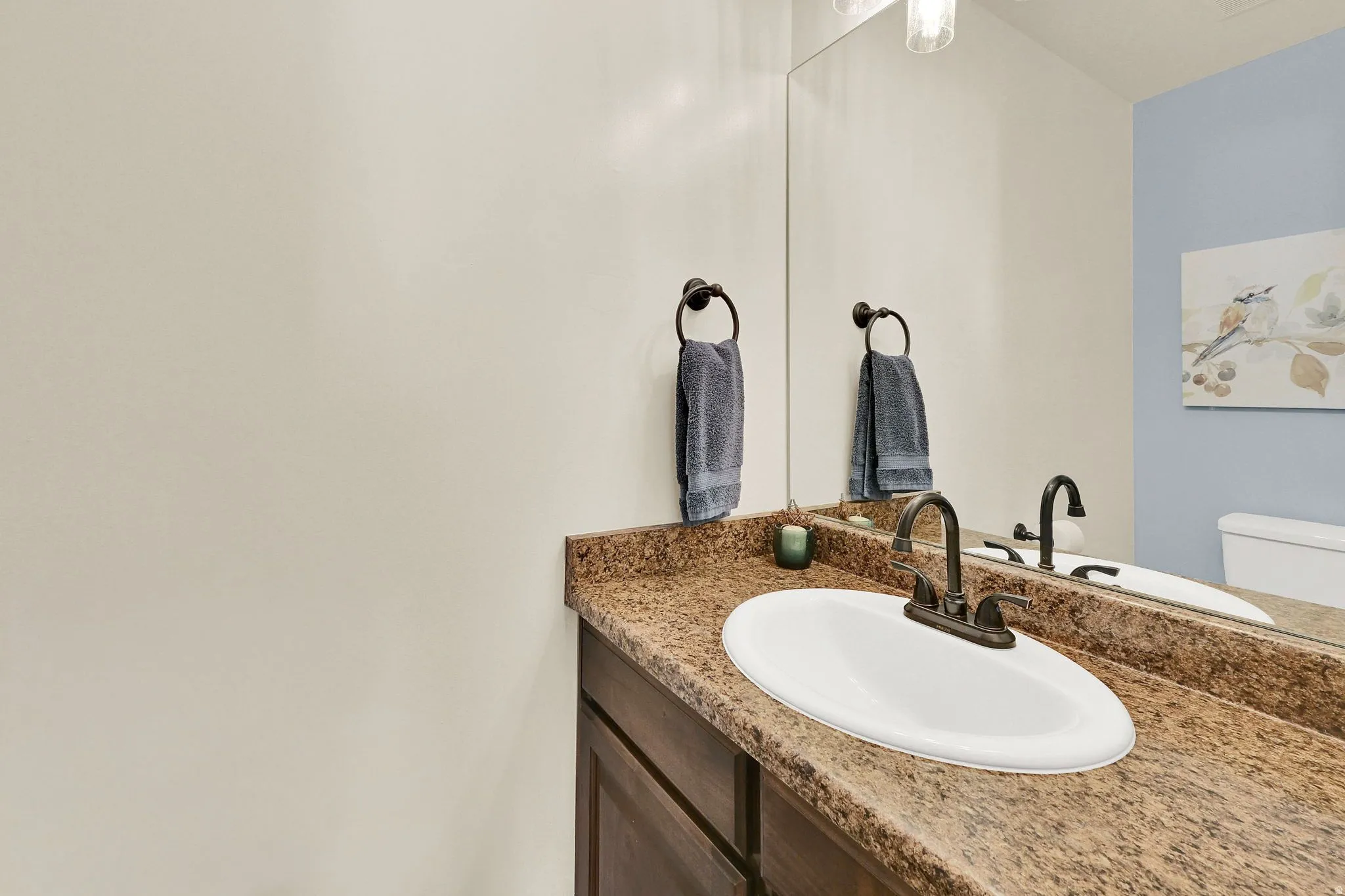 Vanity with an integrated oval sink, bronze-finish faucet, and granite-patterned countertop