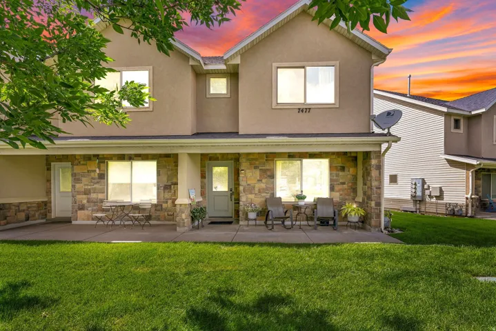 Stucco exterior with stone veneer accents, covered front porch, and expansive front yard