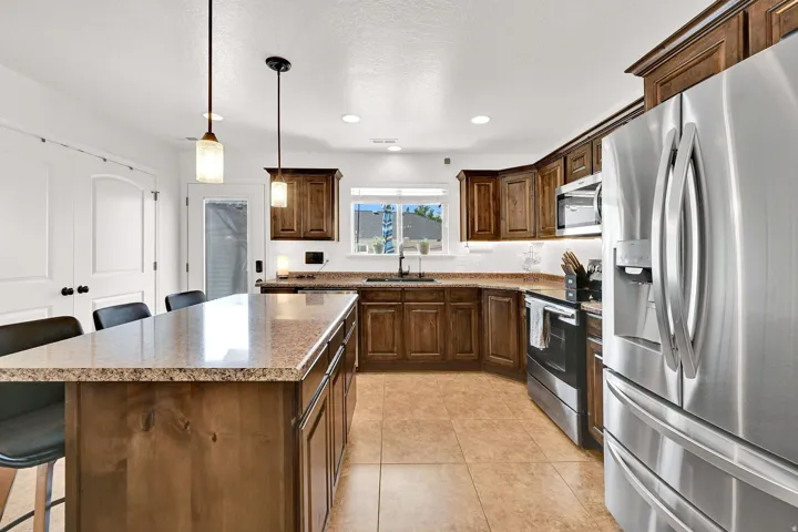 Kitchen featuring a central island with stone-finish countertop, wood cabinetry, stainless steel appliances, and recessed lighting