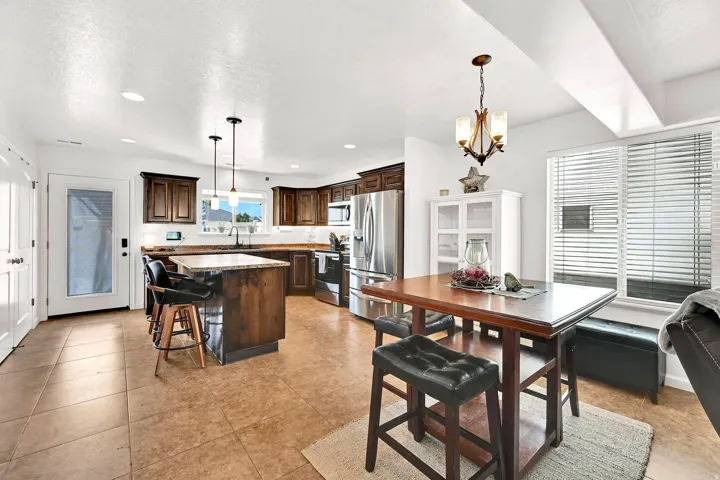 Kitchen featuring stainless steel appliances, dark wood cabinetry, a center island with seating, and tile flooring