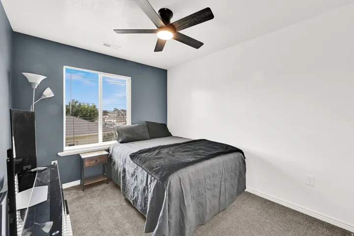 Window with blinds, wall-mounted ceiling fan with integrated lighting, and carpeted flooring