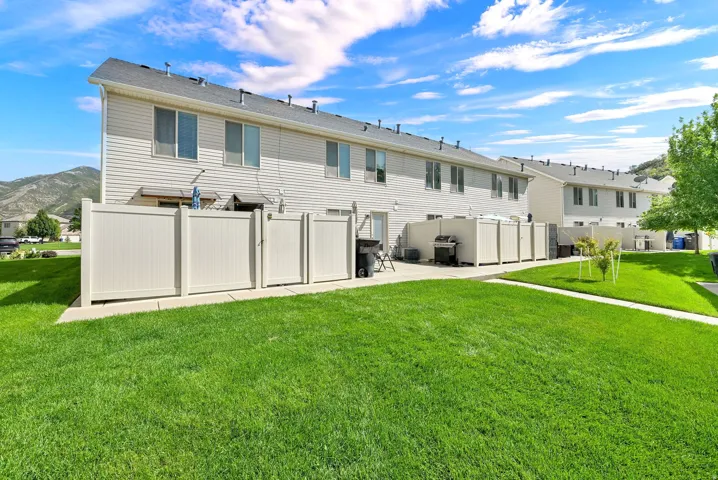Expansive green lawn with a concrete walkway, bordered by white privacy fencing