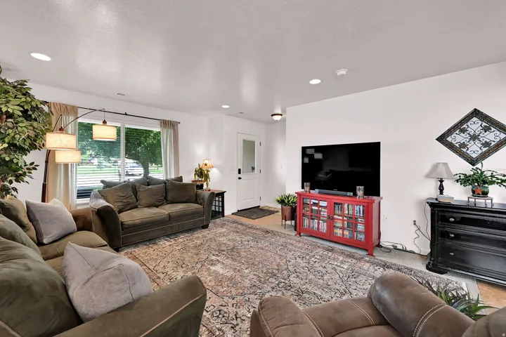 Recessed ceiling lighting, large window with blinds, white interior walls, and a white entry door