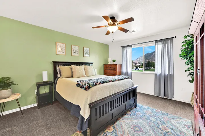Recessed window framing mountain scenery, wood-tone ceiling fan with integrated lighting, wood-finish furniture pieces, and soft carpeting