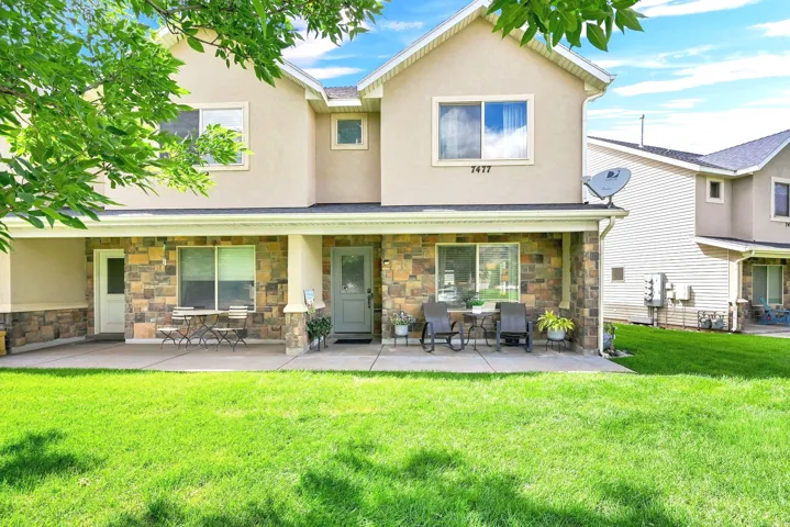 Stucco exterior with stone veneer accents, covered concrete porch, and a light-colored entry door
