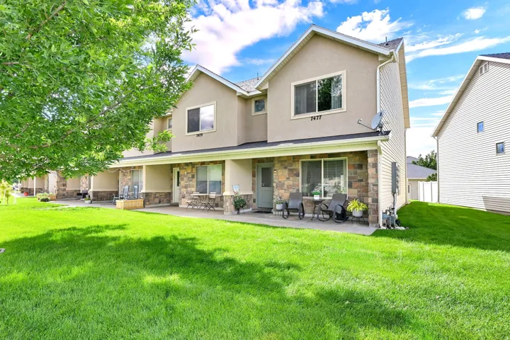 Stucco exterior with stone veneer accents, covered front porch, and expansive front lawn