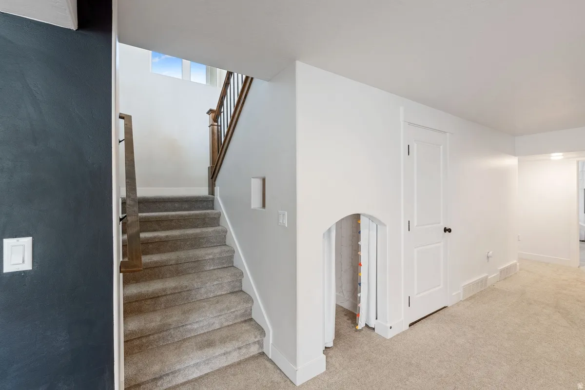 Carpeted staircase with dark wood and black metal balusters