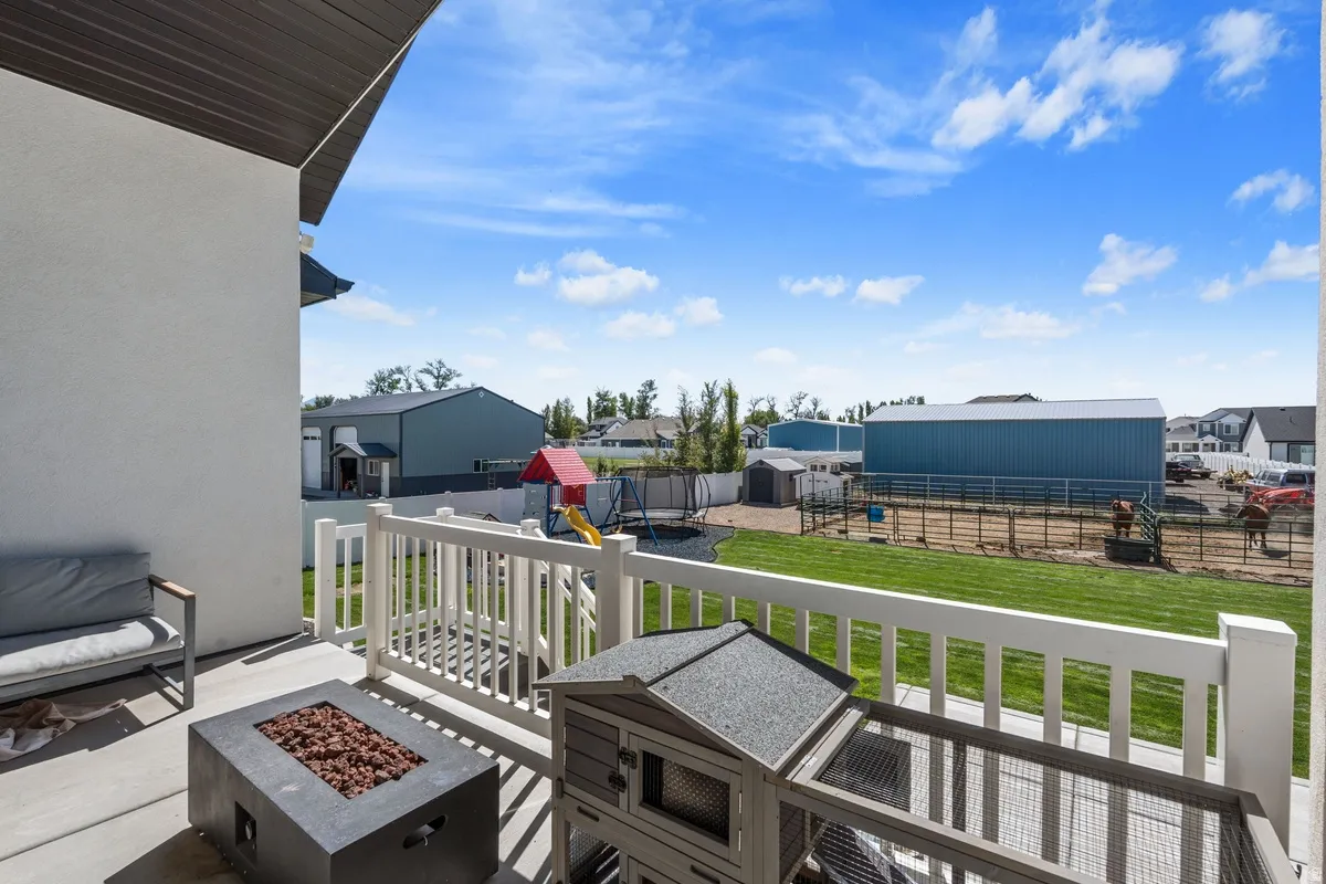 Expansive outdoor balcony with a concrete surface, white railing, and a built-in fire pit