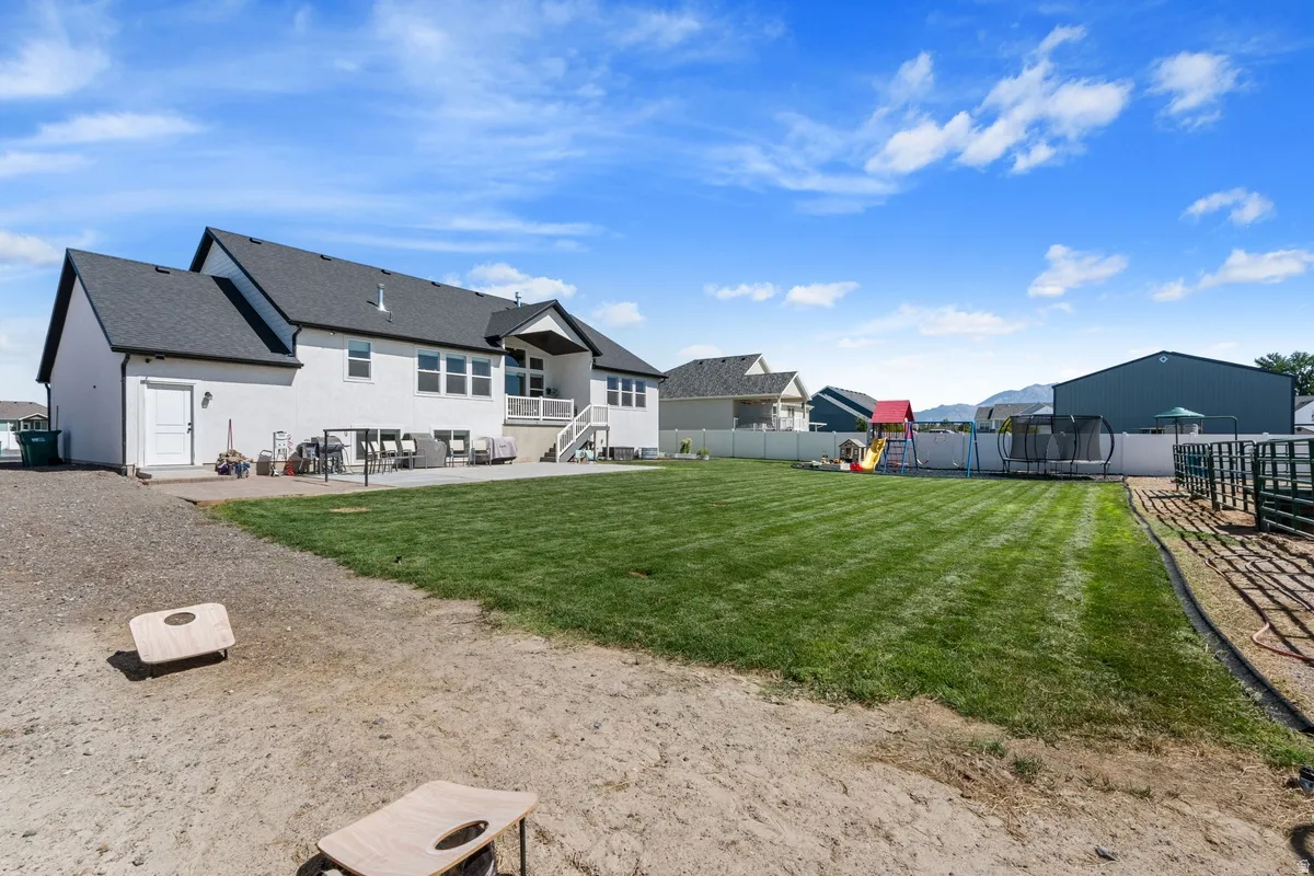 Expansive backyard with a manicured lawn, white privacy fencing, and a gravel area