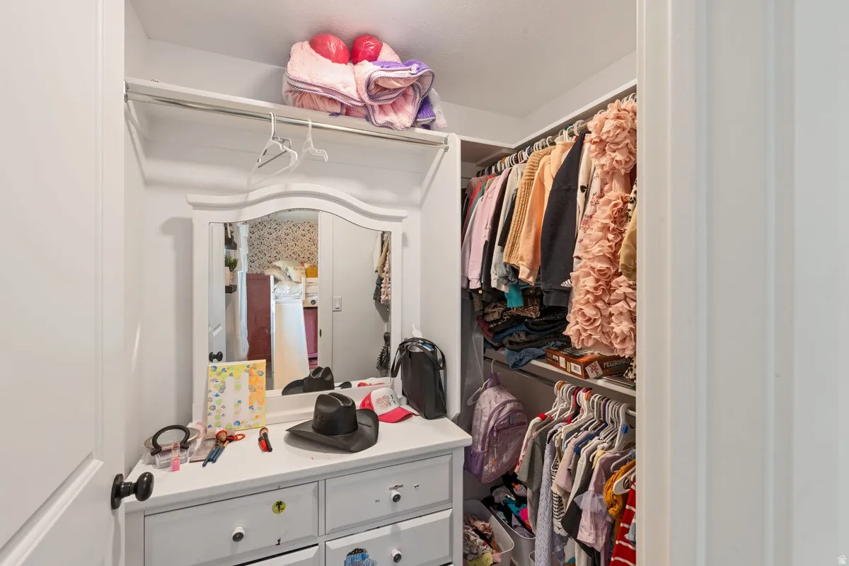Walk-in closet with built-in shelving, hanging rods, and an integrated dressing vanity featuring a mirror