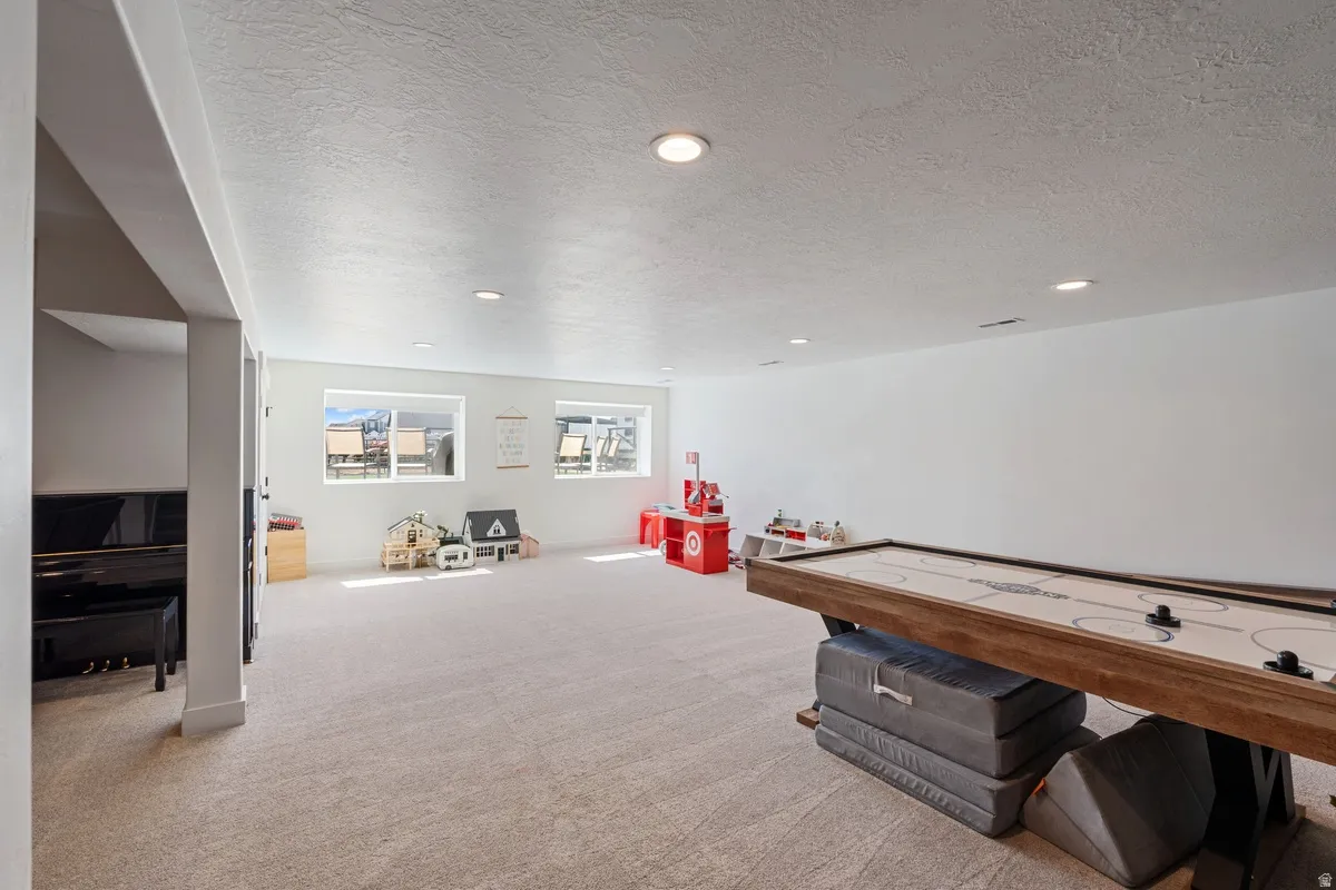 Expansive carpeted area with recessed lighting and multiple windows