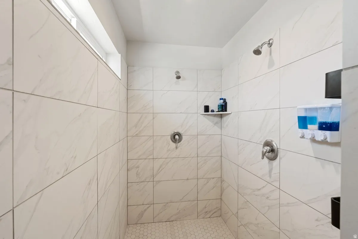 Walk-in shower with large format wall tiling, hexagonal floor tiles, and dual shower heads