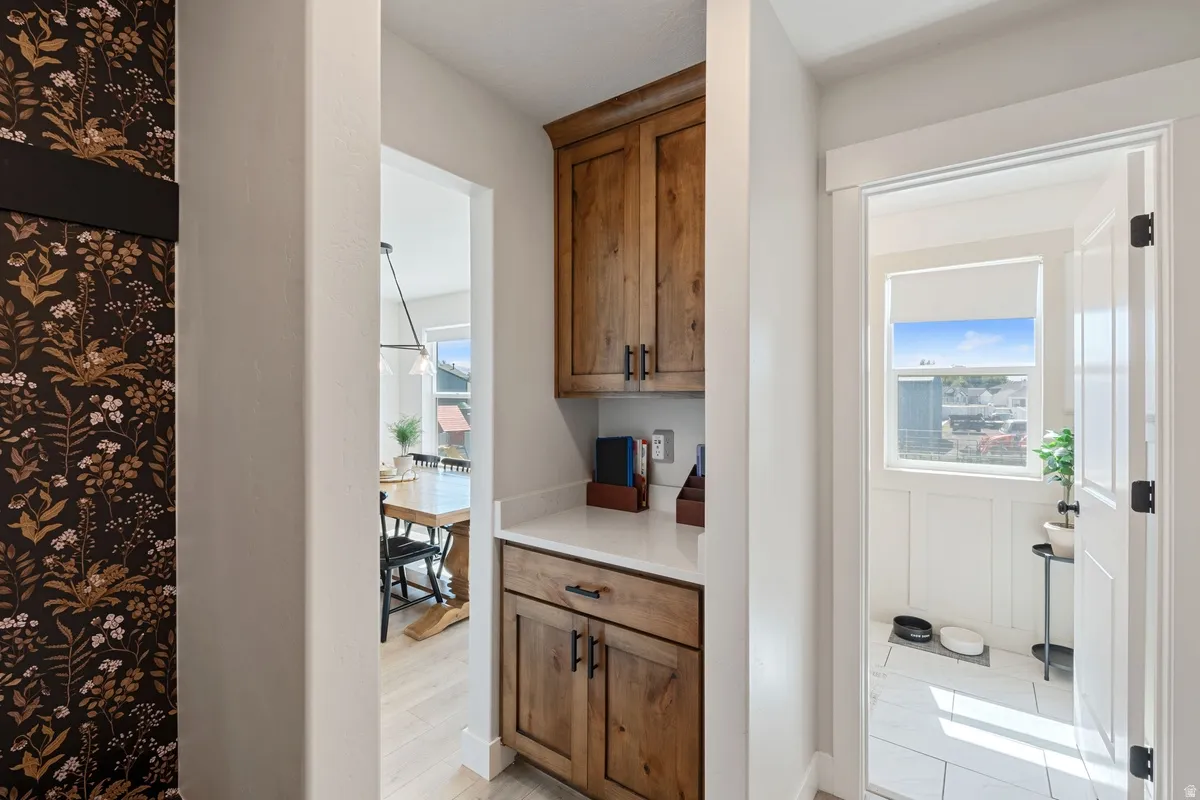 Built-in cabinetry with wood-finish doors and dark hardware, light countertop, and light tile flooring