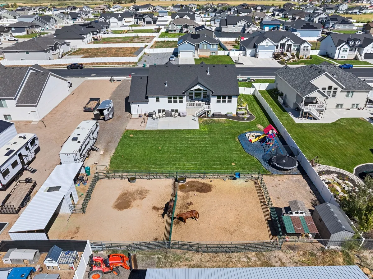Expansive backyard featuring a large green lawn, dedicated pet enclosure, and a structured play area