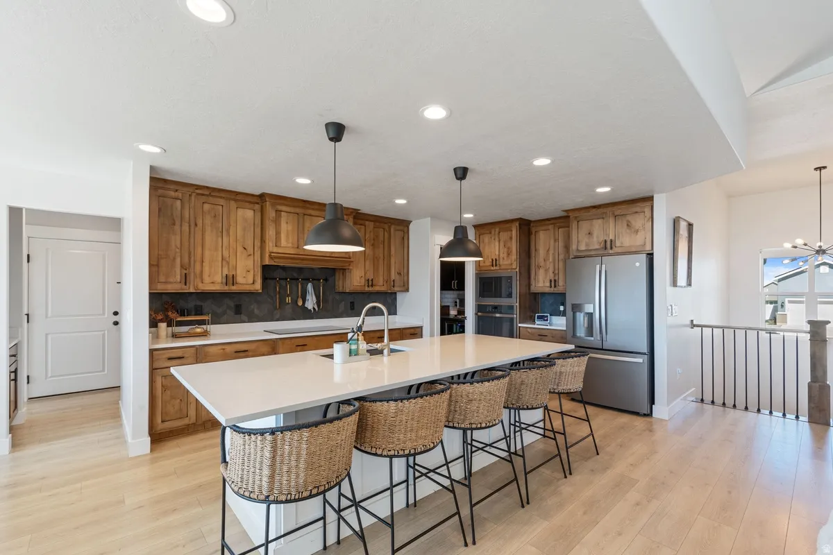 Light wood-finish flooring, recessed lighting, and a large kitchen island with a white countertop