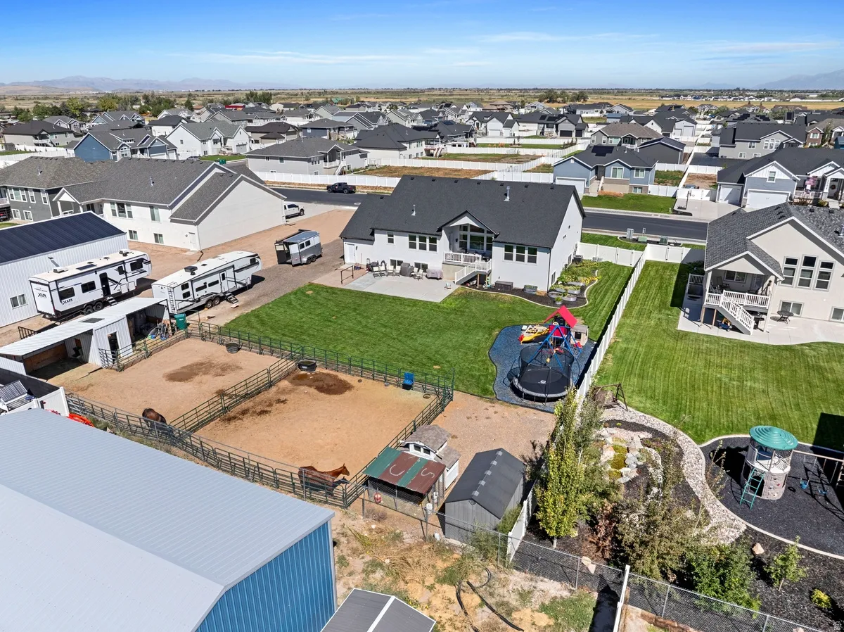 Expansive property featuring a large backyard, multiple fenced paddocks, a substantial outbuilding, and a detached shed