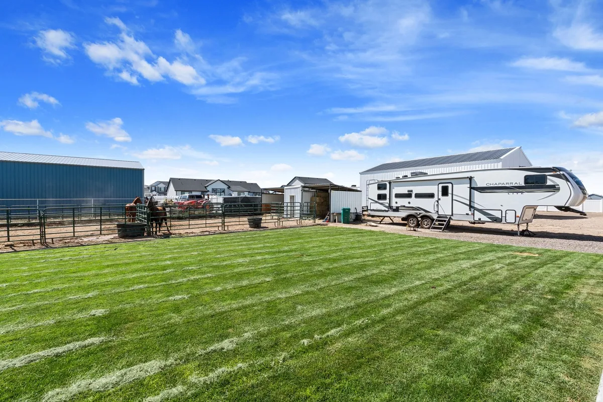 Expansive green lawn, metal fencing, and a metal-sided outbuilding
