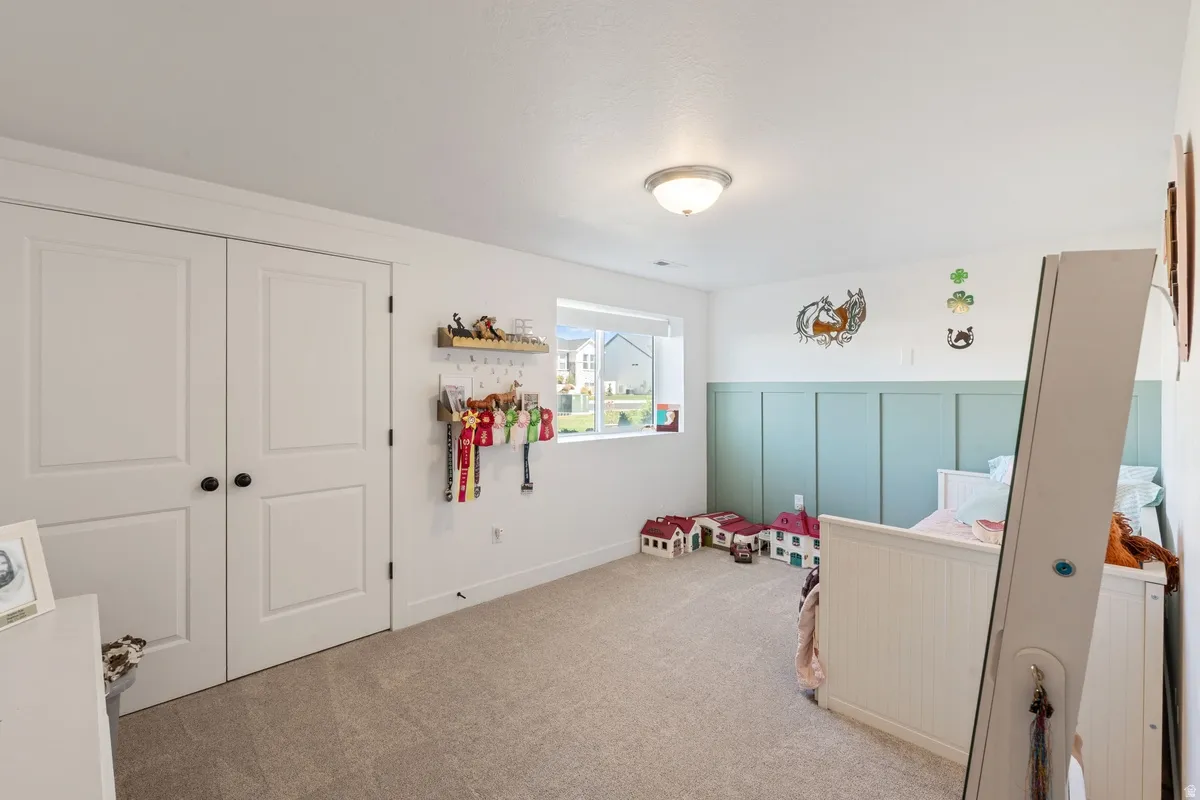 Carpeted flooring, recessed window, flush mount ceiling light fixture, panel accent wall, and double-door closet