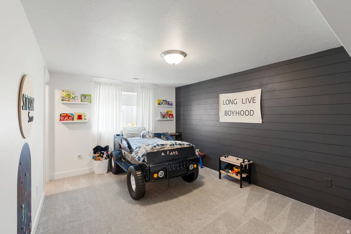 Carpeted flooring with a contrasting dark shiplap accent wall
